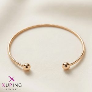 دستبند النگویی (بنگل) زنانه برند ژوپینگ رنگ طلایی با طراحی باز، بدنه طرح بافت ظریف و دو گوی فلزی براق در انتها